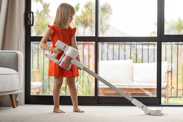 A girl vacuums the living room with a modern wireless vacuum cleaner. Cleaning, wireless technology