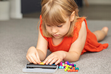 A focused girl is engaged in a colorful logic game. Games for children's development