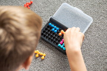 Focused boy deeply engaged in solving a colorful logic puzzle, enhancing his cognitive skills.
