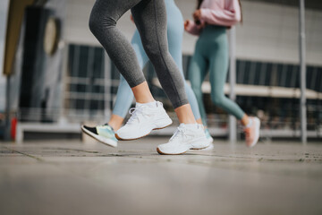 A detailed shot capturing two women's legs in sportswear and sneakers, engaging in fitness or...