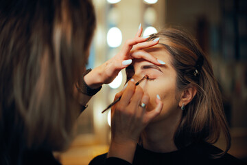 Professional Make-up Artist Applying Eyeshadow with a Brush. Woman having her looks changed through...