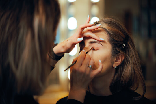 Professional Make-up Artist Applying Eyeshadow with a Brush. Woman having her looks changed through professional makeup 
