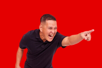 An enraged Asian man aggressively pointing and yelling, with strong heated emotion. Red background.