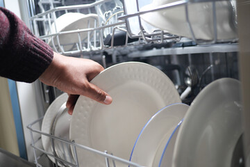 A young woman opens takes out clean white utensils. 