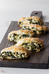 Spinach and feta pastries on a wooden board, ready for sharing.