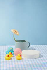 Front view photo with blank round podium to displaying product, surrounded by few baby bath toys and a blue cup with a flower in. Photo for displaying or presentation