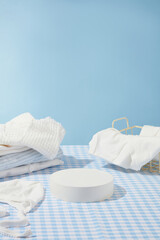 Fototapeta na wymiar Minimalist baby bath style against blue background, several product for baby in bathing placed on plaid blue table cloth with empty podium in center. Front view, space for displaying or advertising