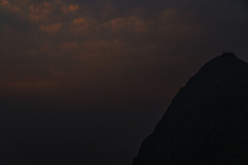 A mountain is silhouetted against a dark sky