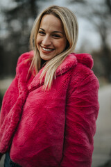 Stylish young woman wearing a bright pink faux fur coat during the chilly winter season