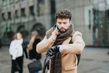 Focused young businessman in a coat talking on a mobile phone during a snowy day, with colleagues...