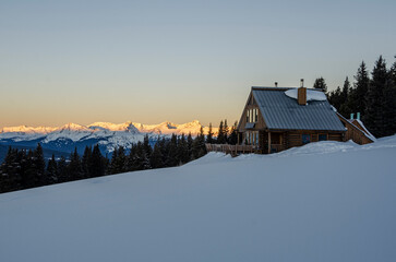 a cabin in the snowy woods at sunrise