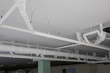 The white pipe system is installed on the ceiling of a building or factory.