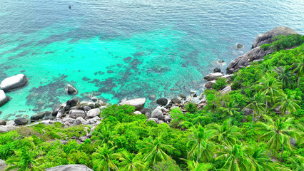 Behold a picturesque coastline adorned with rocky formations, vibrant green forests, and coconut...