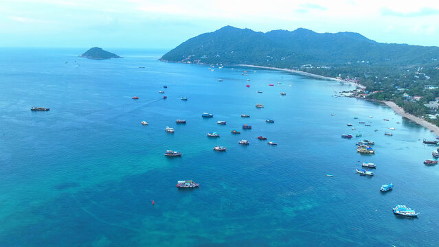Bird's eye panorama of vibrant tropical shores bustling with fishing boats, a mesmerizing scene from above. Flight over the ocean. Tao island, Thailand. Sea background. 


