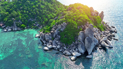 Aerial vista of rugged coastline embraced by vibrant forests and crystalline azure waters, forming...