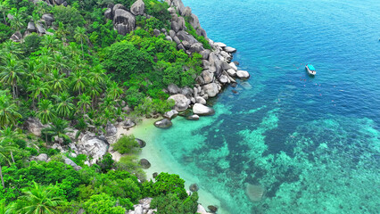 Tropical haven with rocky coasts, vibrant snorkeling scene, and a ship amidst tranquil azure waters. Nature's spectacle from above. Aerial drone. Tao island, Surat Thani Province, Southern Thailand.  © Punyawee