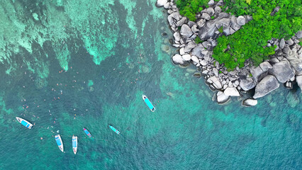 From above, witness a ship amidst snorkeling tourists in the mesmerizing turquoise waters of a tropical oasis. An aerial spectacle of beauty unfolds. Koh Tao, Southern Thailand. Island background.
