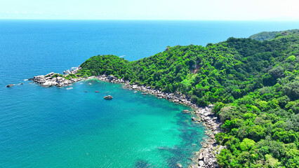 Where lush forests meet the shore, peculiar rock formations adorn the coastline, bathed in the...