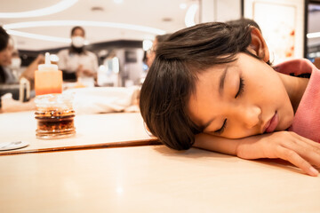 An Asian boy falling asleep on the table while waiting for dinner at a restaurant