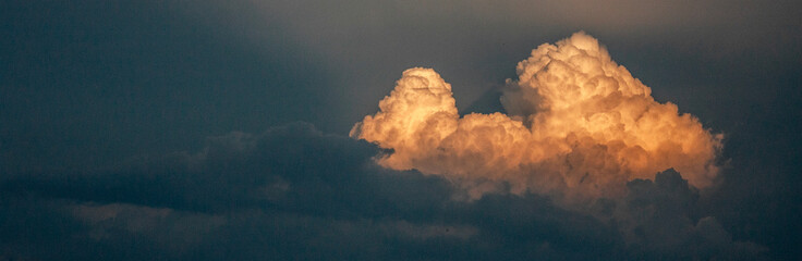 Cloud in the sky at sunset. The cloud is illuminated by the rays of the sun on the dark sky in the...