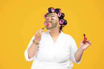 portrait of a fat and happy housewife wearing a natural mask and lipstick isolated on a yellow...