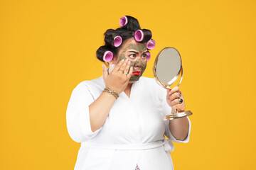 Close-up portrait of fat and angry housewife wearing natural mask looking in the mirror isolated on...