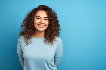 smiling curvy woman looking at camera, standing against blue background, chubby, overweight