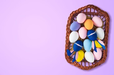 Colorful fresh Easter eggs in basket on colored background