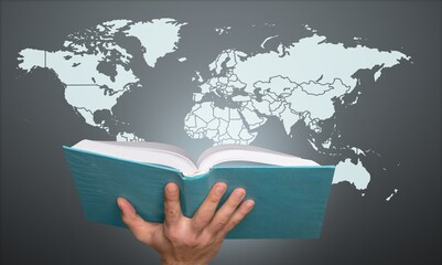 Hand holding Bible book and world map
