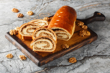 Festive nut roll made from yeast dough with walnuts and honey close-up on a wooden board on the table. Horizontal