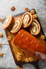 Home baked nut roll, bejgli, traditional sweet bread stuffed with walnut filling closeup on the wooden board on the table. Vertical top view from above
