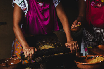 Woman in traditional kitchen preparing native food in clay and stone utensils, sustainable food.