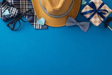 Stylish Father's day setup including a straw hat, glasses, gift box, and bow tie arranged on a...