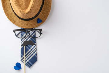 Planning a special Father's Day bash? Top view image featuring a straw hat, elegant tie, eyeglasses, mustaches on stick, and paper hearts on white, perfect for your greeting or ad