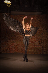 Beautiful girl a dark angel with black wings posing on the dark background. Angel of the night concept.