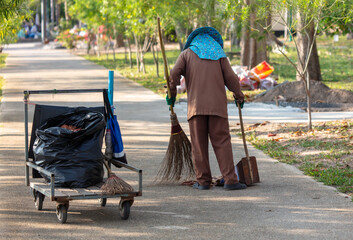 A man sweeps the street in a tropical park