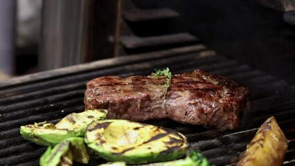 burning fire, coals, embers, in oven in restaurant.mixing smoldering charcoal creating fiery dust.beef steak and vegetables on grill.many pieces of filet mignon, medium rare.chef turn mean with tongs.