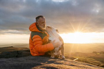 Face of a senior mature gentleman with bulldog sitting on a rock, enjoying calm day