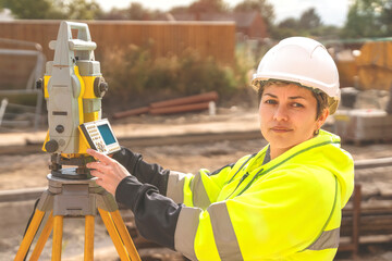 Close-up portrait of a woman site engineer surveyor working with theodolite total station EDM...