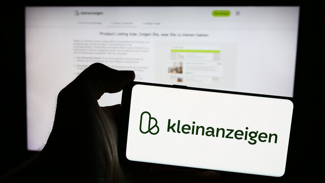 Stuttgart, Germany - 04-13-2024: Person holding mobile phone with logo of German classifieds platform company kleinanzeigen.de GmbH in front of web page. Focus on phone display.