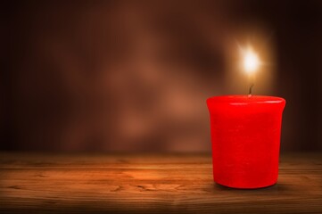 A lit candle with bright flame on dark background