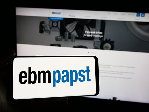 Stuttgart, Germany - 04-13-2024: Person holding smartphone with logo of German electric motor company EBM-Papst Gruppe in front of website. Focus on phone display.