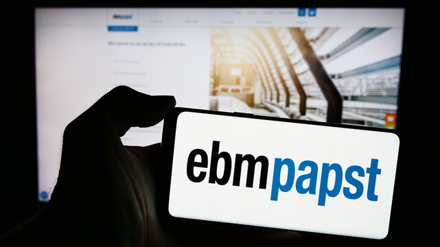Stuttgart, Germany - 04-13-2024: Person holding mobile phone with logo of German electric motor company EBM-Papst Gruppe in front of business web page. Focus on phone display.