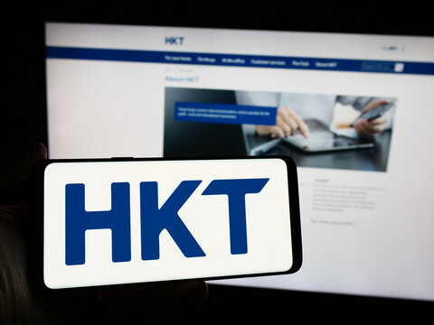 Stuttgart, Germany - 04-13-2024: Person holding smartphone with logo of telecommunications company HKT Limited (Hong Kong Telecom) in front of website. Focus on phone display.