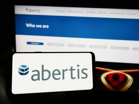 Stuttgart, Germany - 04-13-2024: Person holding smartphone with logo of Spanish toll road company Abertis Infraestructuras S.A. in front of website. Focus on phone display.