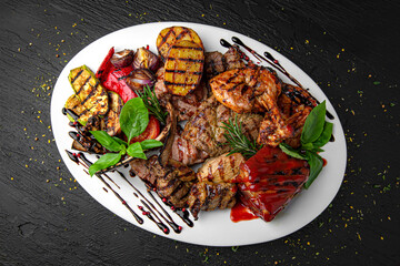Meat set. A dish of different types of meat: beef steak, pork cuts and ribs, chicken kebab and grilled quail, lamb ribs. Menu for a pub on a dark background.
