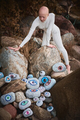 Young hairless girl with alopecia in white futuristic costume looking at surreal landscape with lot of rocks eyes, symbolizing connection between human spirit and earth