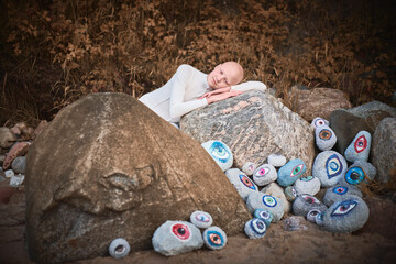 Young hairless girl with alopecia in white futuristic costume lying pensively among surreal landscape with many eyes stones, symbolizes introspection and reevaluation of individuality