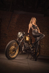 Sexy girl a motorbiker posing near retro style motorcycle.