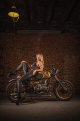 Fototapeta na wymiar Sexy girl a motorbiker posing near retro style motorcycle.